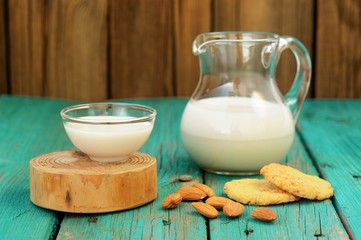 Homemade fresh almond milk in glass jar and glass bowl, with hom