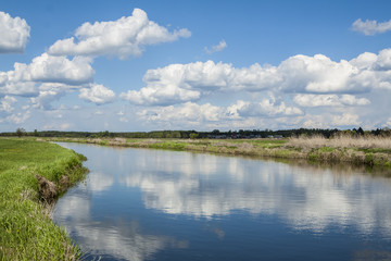 Obraz na płótnie Canvas Quiet river, clouds reflected in the calm water.