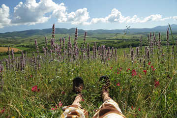 resting legs on flowering meadow in tuscan countryside