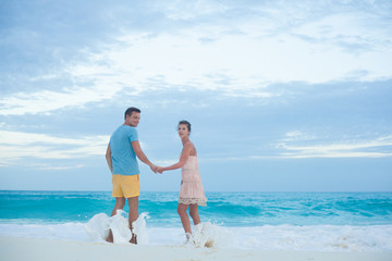 Back view of couple in bright clothes having fun at tropical