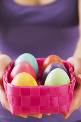Fototapeta na wymiar A woman holding a basket of coloured eggs