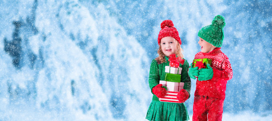Kids with Christmas presents in snowy winter park