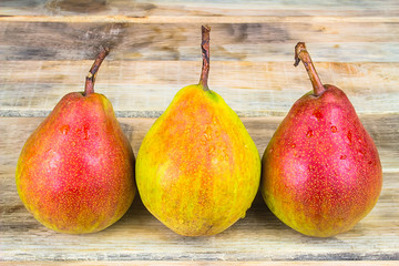 Three ripe yellow and red pears on rustic wooden background