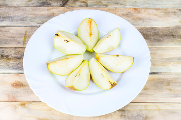 Sliced fresh pears in white plate on rustic wooden table