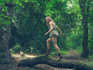 Young woman walking on log in forest