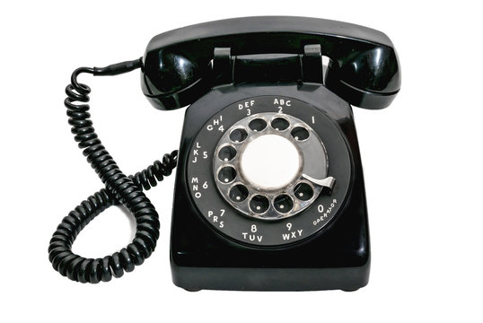 Old black vintage rotary dial telephone on white background