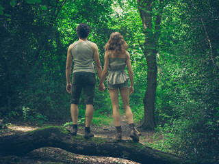 Young couple standing on a log in the forest