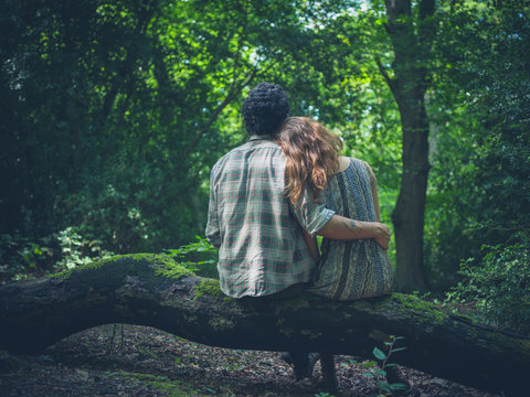 Young couple embracing on log in forest