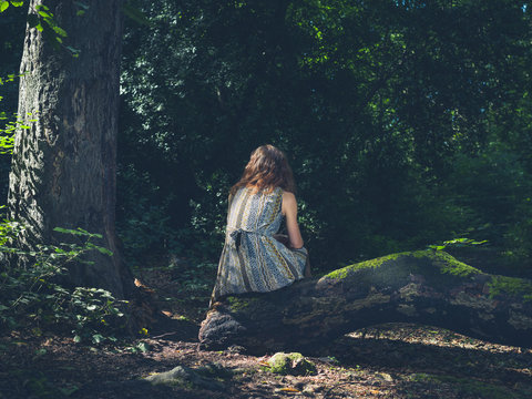 Woman sitting on log in forest