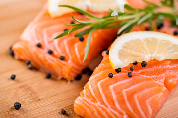 Close up on fresh salmon fillet with rosemary, pepper and lemon.