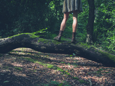 Young woman standing on a log in the forest