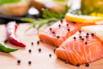 Close up on fresh salmon fillet with rosemary, paprika, pepper and lemon.