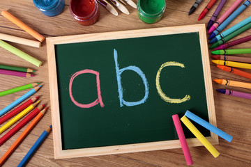 ABC written on a small blackboard on a child student desk with crayons and pencils basic alphabet...