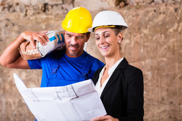 Architect and construction worker on site with plan