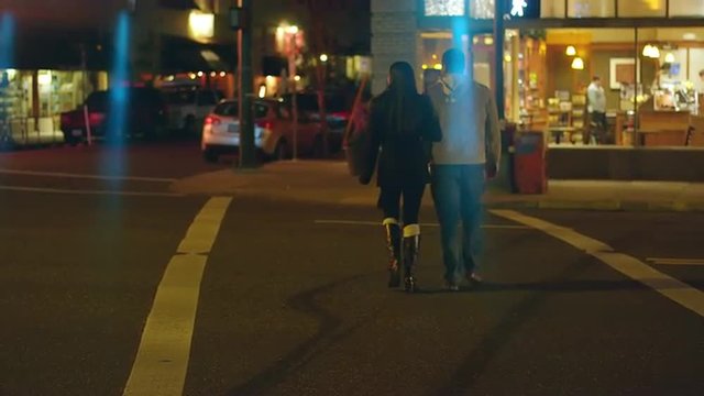 A young couple walking downtown at night