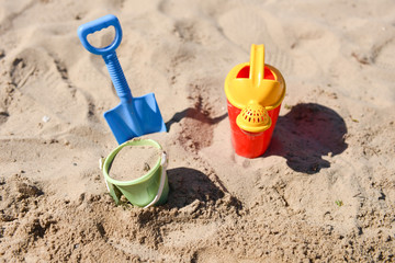 Colorful summer beach toys, bucket, sprinkler and shovel on sand