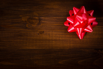 Red bow on wooden brown planks