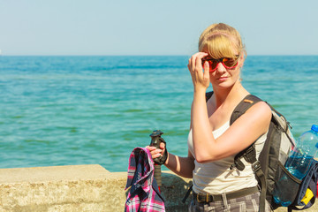 young woman with backpack hiking on sea coast