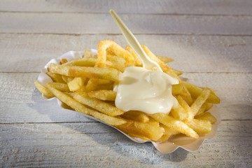 Chips with mayonnaise and plastic fork on paper plate