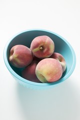 Several peaches in a blue bowl