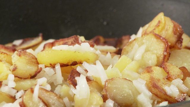 Fried potatoes being seasoned with salt and pepper