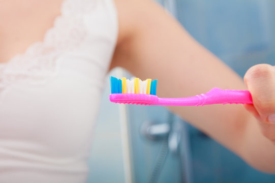 Woman Hand Holding Toothbrush In Bathroom