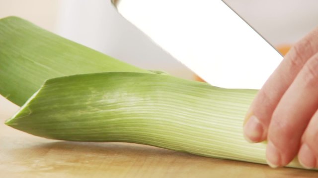 A leek being cut in half lengthways and chopped