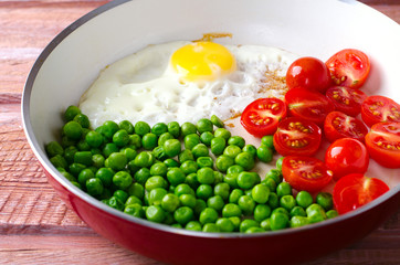 Breakfast with fried egg, green peas and cherry tomatoes