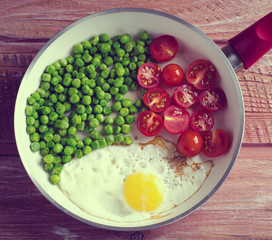 Breakfast with fried egg, green peas and cherry tomatoes