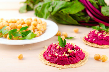 Beet hummus with peanuts and parsley on thin wafers