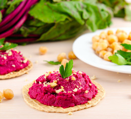 Beet hummus with peanuts and parsley on thin wafers