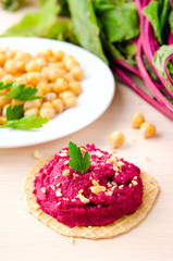 Beet hummus with peanuts and parsley on thin wafers