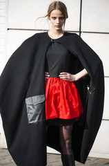 Beautiful fashion girl in stylish coat poses outdoors
