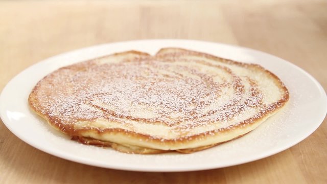 Pancakes being dusted with icing sugar