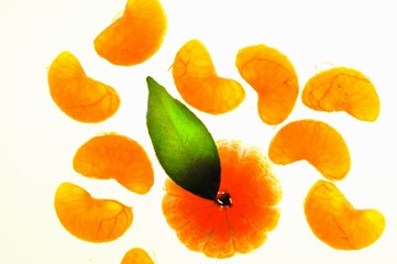 A peeled mandarin with a leaf and wedges