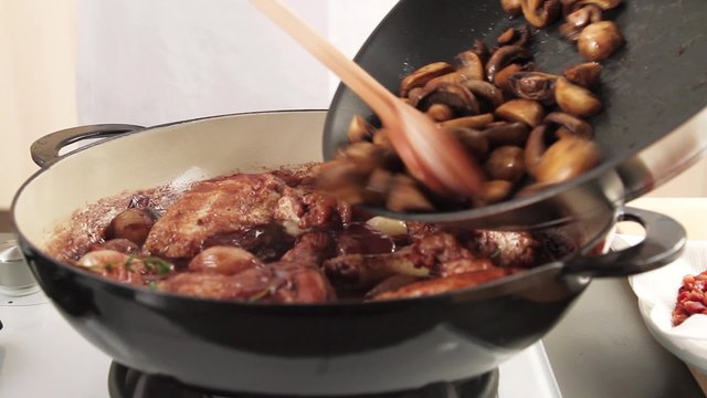 Fried mushrooms being added to coq au vin