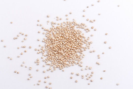 white quinoa seeds scattered on white background