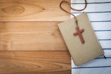 wooden Christian cross necklace on holy Bible on wood table