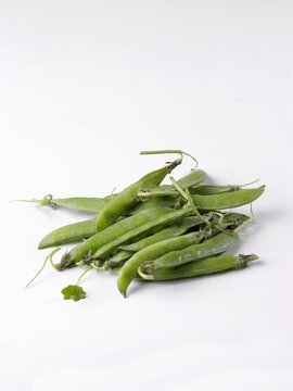 Young peapods on a white surface