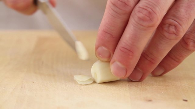 Garlic cloves being finely sliced