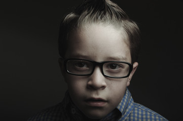 Fototapeta na wymiar Low key closeup portrait of little boy looking sad