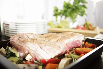 Pork belly on a bed of vegetables, ready to roast