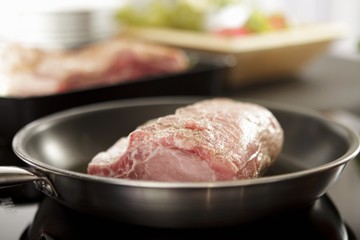 Raw pork roasting joint in a pan