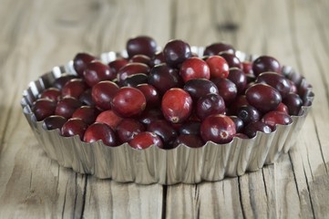 Cranberries in a tart dish on a wooden surface