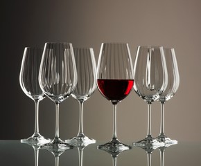 Five empty wine glasses and one full one