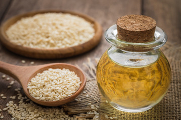 Sesame oil in glass jar and sesame seeds on wooden spoon