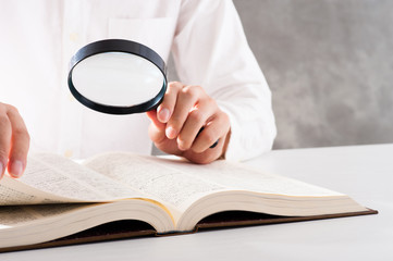 虫眼鏡を使って本を調べる男性