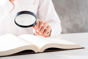 虫眼鏡を使って本を調べる男性