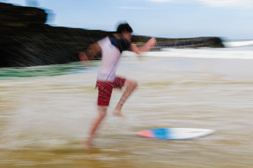 Fototapeta premium Young man running and jumping on a skim board on Maui, Hawaii, U
