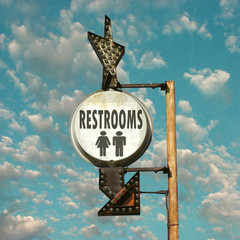 aged and worn vintage photo of restroom sign with arrow